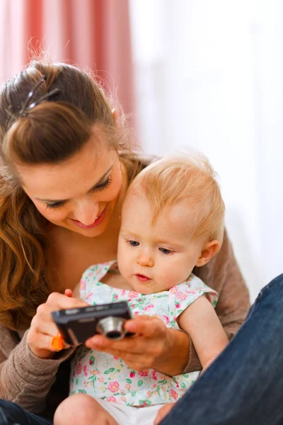 Young mother showing interested baby photos in camera — Stock Photo, Image