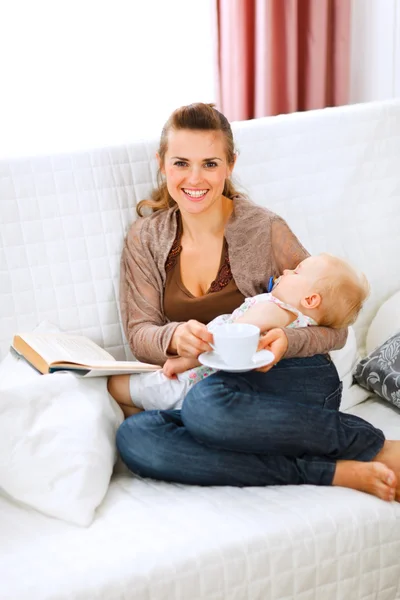 Young mother resting while baby sleep by having tea and reading — Stock Photo, Image