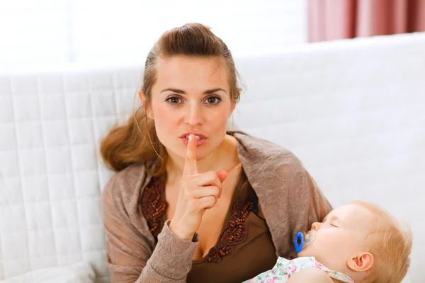 Young mama holding sleeping baby and showing shh gesture — Stock Photo, Image