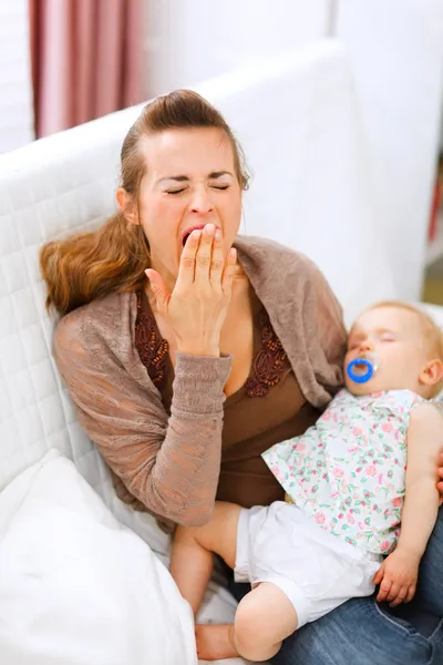 Joven madre con bebé dormido en las manos bostezando —  Fotos de Stock