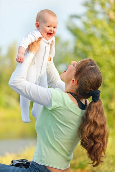 Szczęśliwą matką, bawiąc się śmieje dziecko dziewczyna w parku — Zdjęcie stockowe