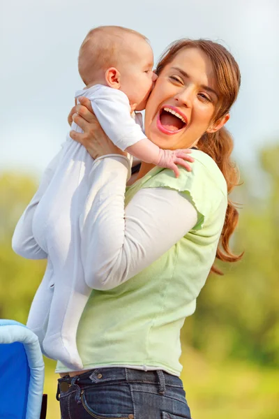 Малышка целуется, держа свою счастливую мать — стоковое фото