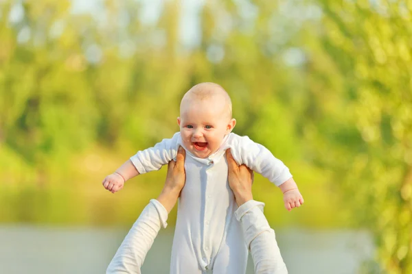 Anyja keze gazdaság nevető imádnivaló baba napos levelek ellen — Stock Fotó