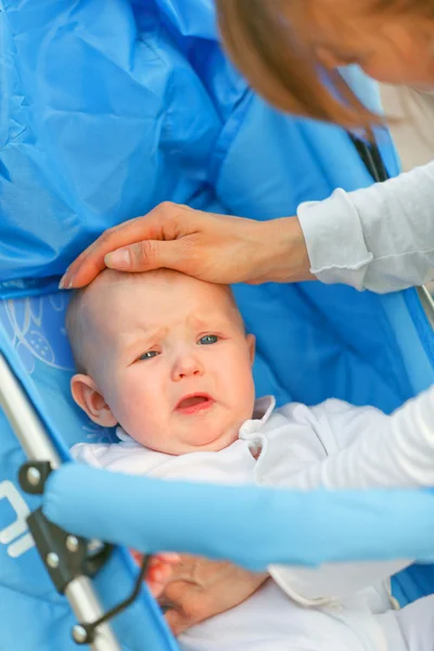 Caring mother soothing sitting in stroller crying baby — Stock Photo, Image