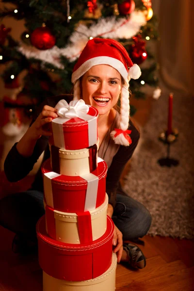 Χαμογελώντας νεαρή γυναίκα κοντά χριστουγεννιάτικο δέντρο που ψάχνουν από το σωρό — Φωτογραφία Αρχείου