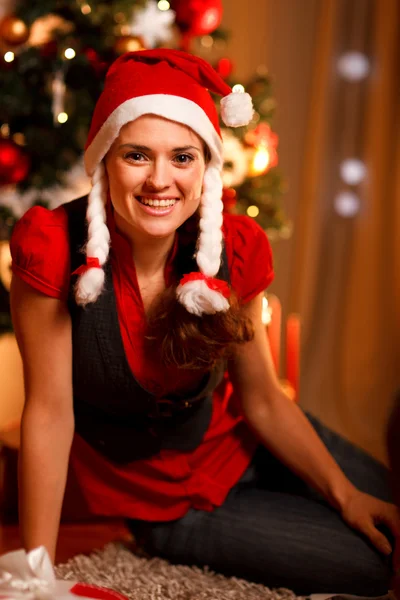 Gülümseyen kadın Noel ağacının yanında oturan — Stok fotoğraf