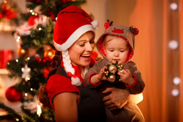 Sorrindo mãe brincando com bebê encantador perto da árvore de Natal — Fotografia de Stock