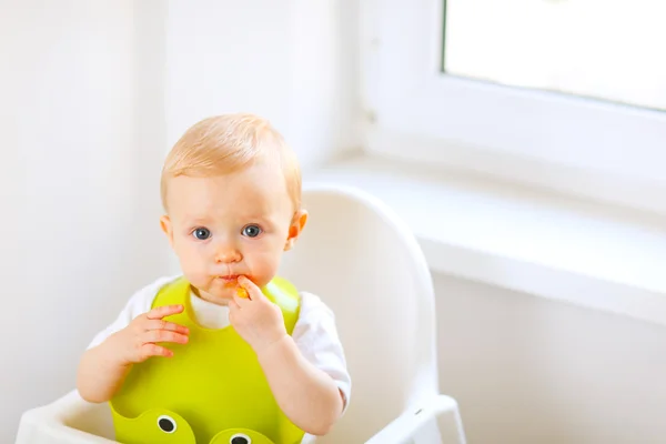 赤ちゃん用の椅子に座って食べるまみれて赤ちゃんの肖像画 — ストック写真