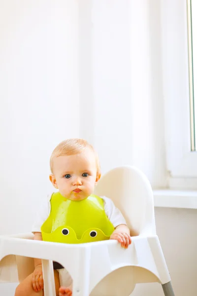 Retrato de adorável comer bebê manchado sentado em cadeira de bebê — Fotografia de Stock
