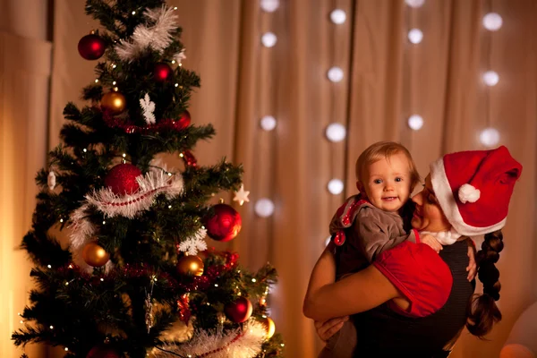 Porträtt av bedårande barn på mamas hand nära julgran — Stockfoto
