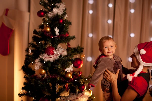 Retrato de bebé encantador en la mano de mamas cerca del árbol de Navidad — Foto de Stock