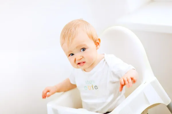 赤ちゃん用の椅子に座っていると変な顔を作るかわいい赤ちゃん — ストック写真
