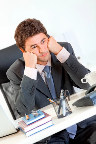 Ofis Masası ve tutmak başında eller üzerinde oturan sıkılmış iş adamı — Stok fotoğraf