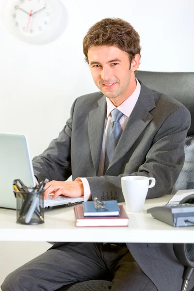 Homem de negócios moderno sentado na mesa de escritório e trabalhando no laptop — Fotografia de Stock