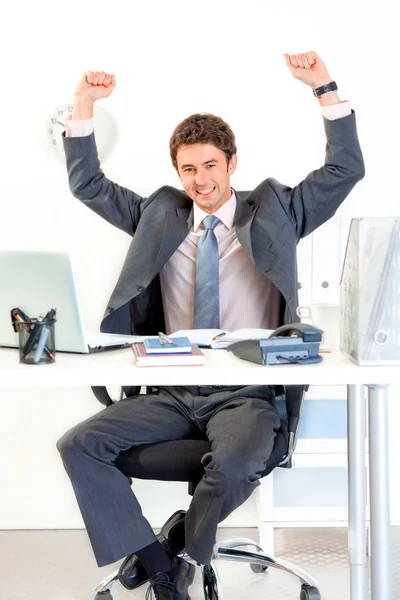 Возбужденный бизнесмен, сидящий за столом офиса и радующийся успеху — стоковое фото