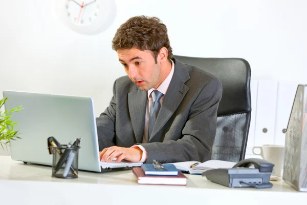 Uomo d'affari moderno sorpreso guardando in computer portatile a ufficio — Foto Stock