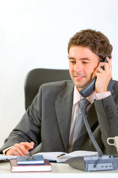 Homem de negócios moderno sentado no escritório e falando telefone — Fotografia de Stock