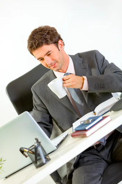 Empresário moderno feliz bebendo café e olhando no laptop — Fotografia de Stock