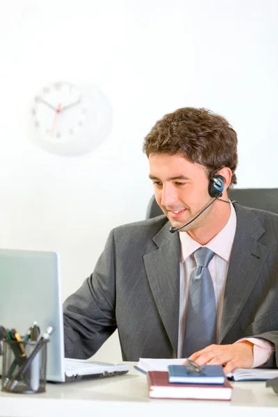 Sonriente hombre de negocios moderno con auriculares mirando en el ordenador portátil — Foto de Stock