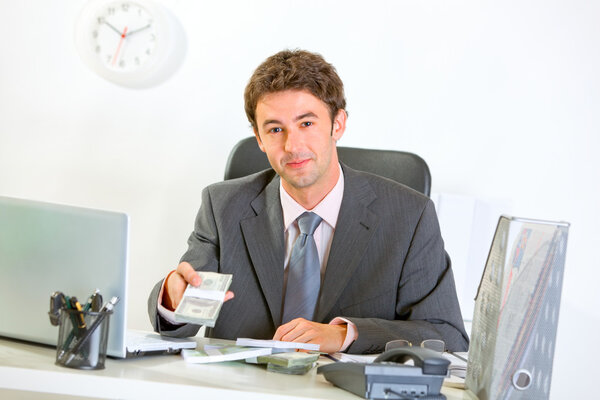 Modern businessman sitting at office desk and giving money packs