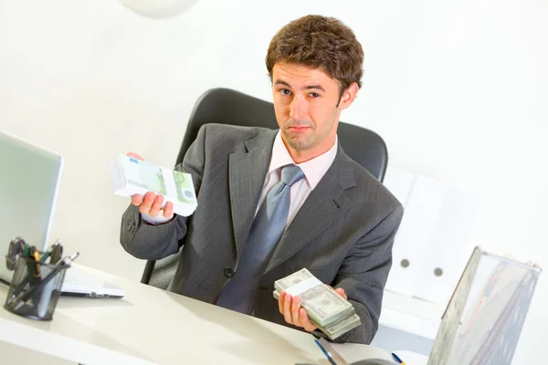 Seriöser Geschäftsmann sitzt am Schreibtisch und bietet mo — Stockfoto
