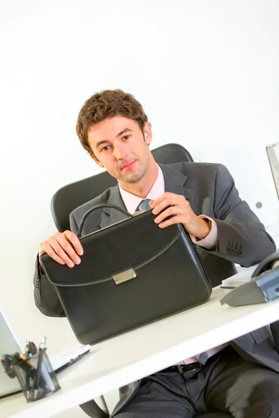 Selbstbewusster Geschäftsmann sitzt mit Aktentasche am Schreibtisch — Stockfoto