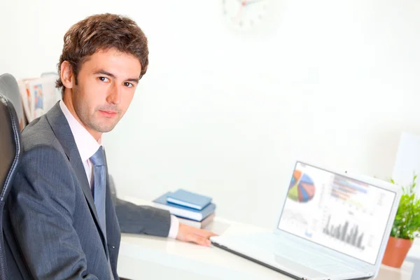 Ernstige zakenman zit aan bureau met laptop — Stockfoto