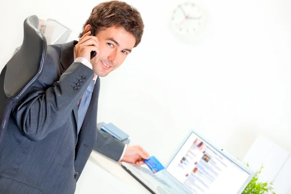 Uomo d'affari sorridente in ufficio che effettua l'acquisto per telefono e carta di credito — Foto Stock