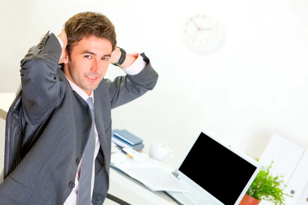 Pleased businessman relaxing on armchair at office desk — Stock Photo, Image