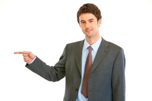 Smiling modern businessman pointing finger at copy space — Stock Photo, Image