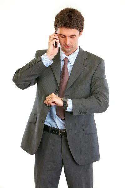 Homem de negócios moderno falando no telefone e olhando no relógio — Fotografia de Stock