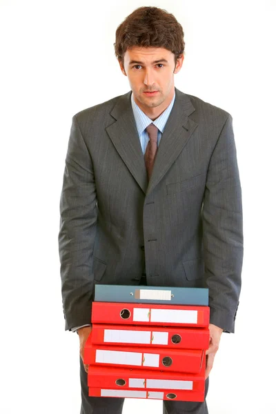 Jovem empresário estressante segurando em mãos pilha pesada de folde — Fotografia de Stock