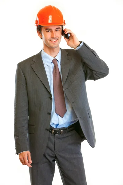 Hombre de negocios sonriente con casco en la cabeza hablando por teléfono móvil — Foto de Stock