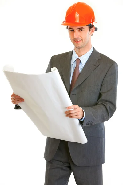 Uśmiechający się inżynier w kask, trzymając w ręku planu budynku — Zdjęcie stockowe