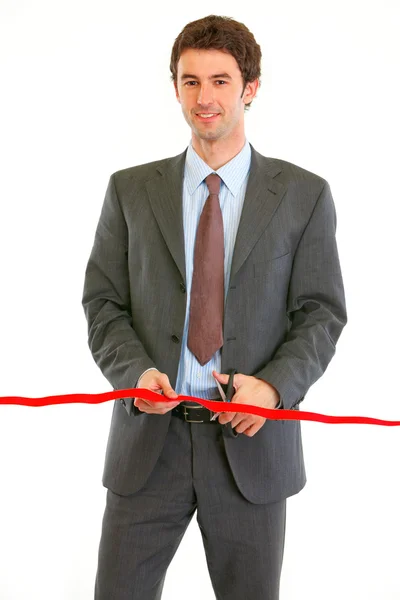 Smiling modern businessman cutting red ribbon — Stock Photo, Image