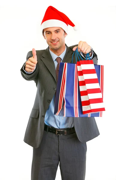 Heureux homme d'affaires moderne à Santa Hat avec des sacs à provisions montrant — Photo