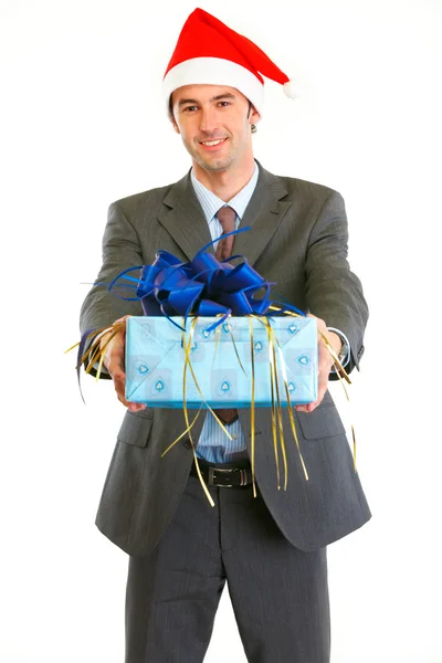 Улыбающийся современный бизнесмен в Санта-шляпе представляет подарок — стоковое фото