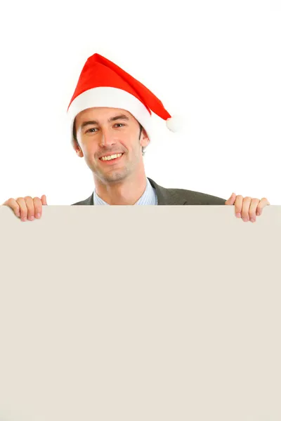 Smiling guy in Santa hat holding blank billboard — Stok fotoğraf