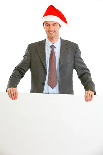 Happy modern businessman in Santa Hat showing blank billboard — Stock Photo, Image
