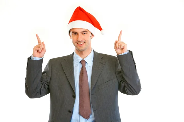Sorridente giovane uomo d'affari a Babbo Natale che punta il dito verso l'alto — Foto Stock