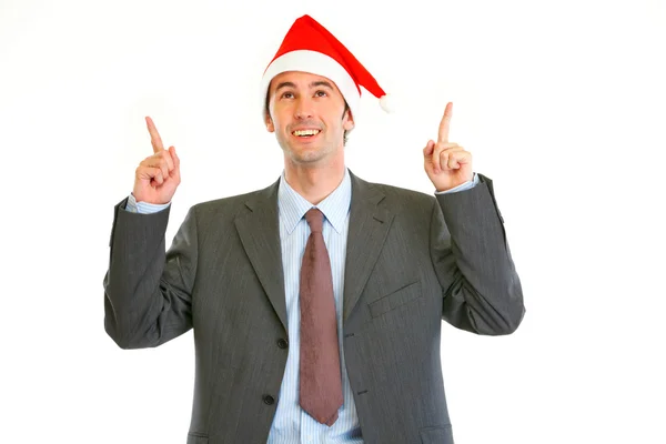 Smiling modern businessman in Santa Hat pointing up — Stock Photo, Image