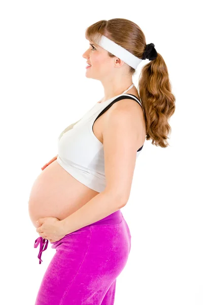 Lächelnde schöne schwangere Frau in Sportbekleidung, die ihren Bauch hält — Stockfoto