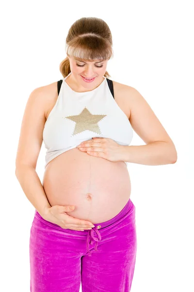 Беременная женщина в спортивной одежде держит живот — стоковое фото