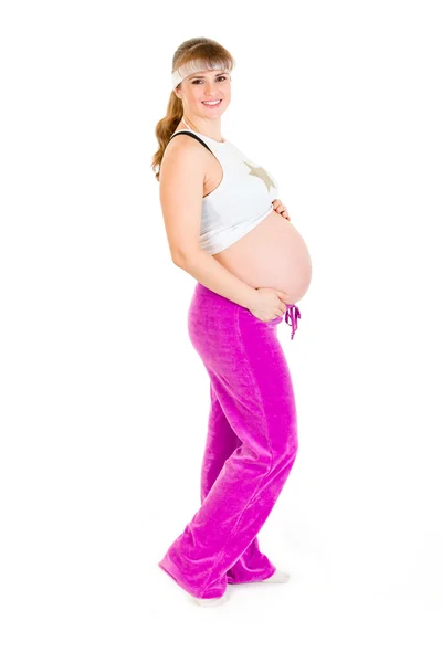 Улыбающаяся красивая беременная женщина в спортивной одежде, держащая животик — стоковое фото