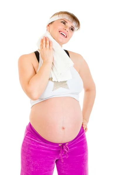 Mujer embarazada sonriente limpiándose la cara con toalla después de hacer ejercicio —  Fotos de Stock