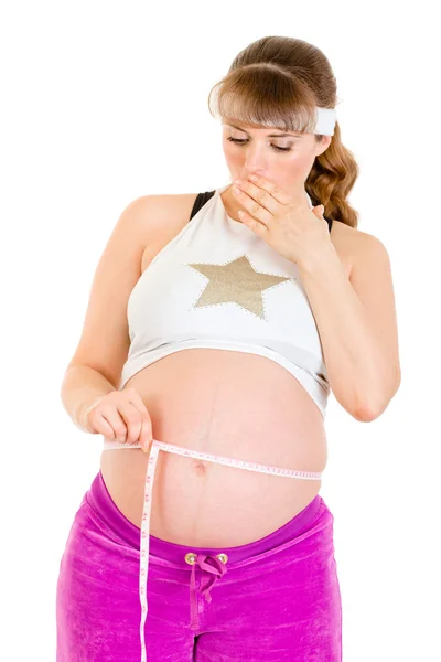Surprised beautiful pregnant woman measuring her belly — Stock Photo, Image