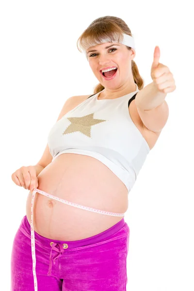 微笑怀孕妇女举行卷尺和显示竖起大拇指的手势 — 图库照片