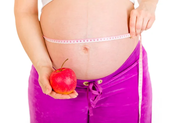 Schwangere misst ihren Bauch und hält Apfel in der Hand. Nahaufnahme. — Stockfoto