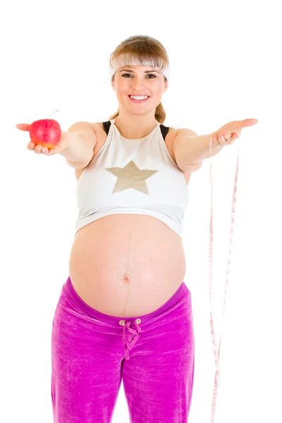 Χαμογελώντας όμορφη έγκυο γυναίκα, κρατώντας την ταινία μέτρο και μήλο — Φωτογραφία Αρχείου