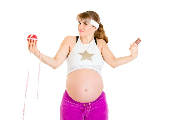 リンゴやチョコレートですか？選択を作る美しい妊娠中の女性 — ストック写真
